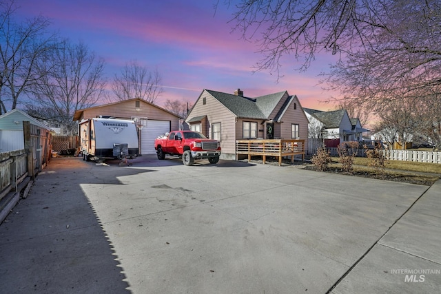 view of front of house featuring a detached garage, fence, and an outdoor structure