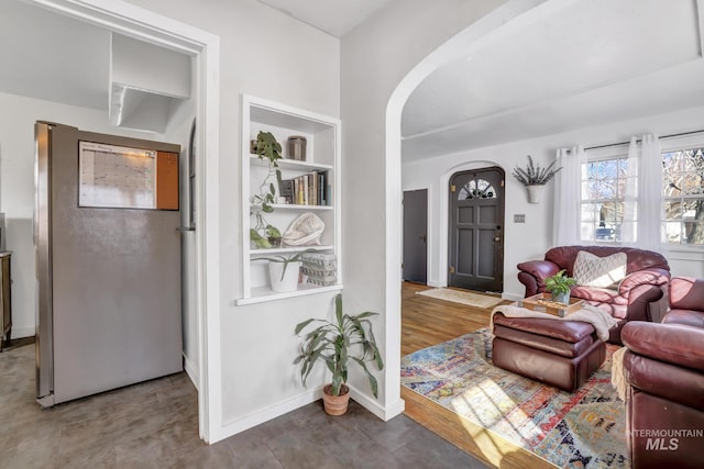 living area with built in features, arched walkways, and baseboards