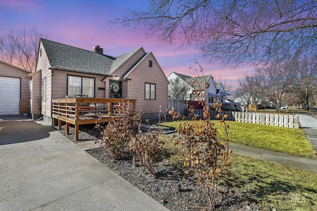 view of front of property featuring a deck, fence, a chimney, and a shingled roof