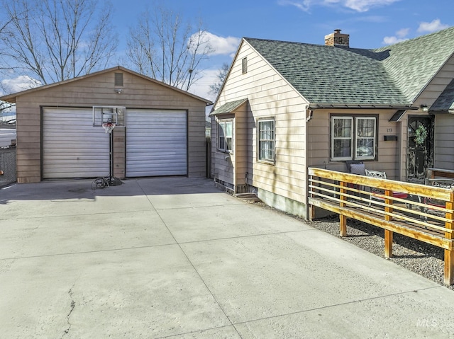 view of side of property with a garage, roof with shingles, an outdoor structure, and a chimney