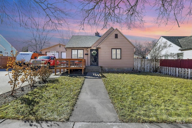 view of front of house featuring a front yard, fence, a chimney, and a wooden deck