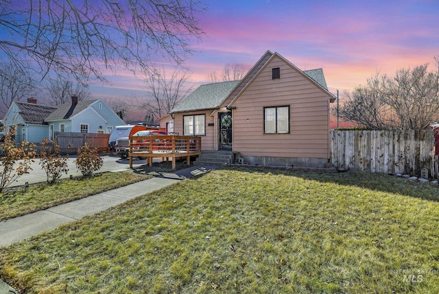 bungalow featuring roof with shingles, a front yard, fence, and a wooden deck