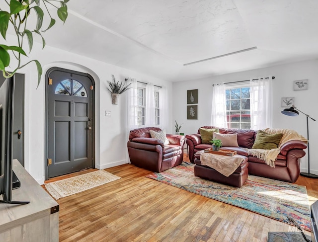 living room featuring light wood-style floors, arched walkways, and baseboards