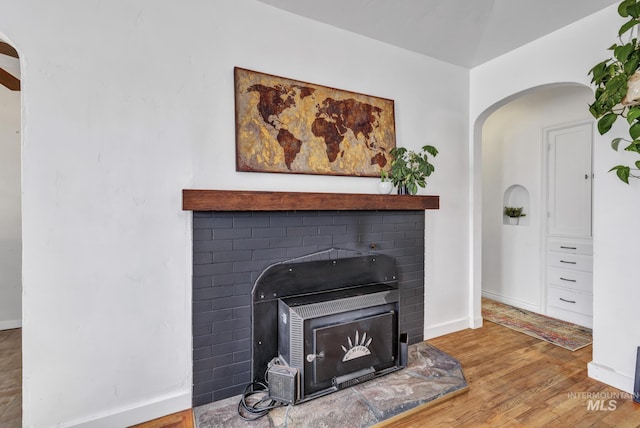 interior details with arched walkways, wood finished floors, and baseboards