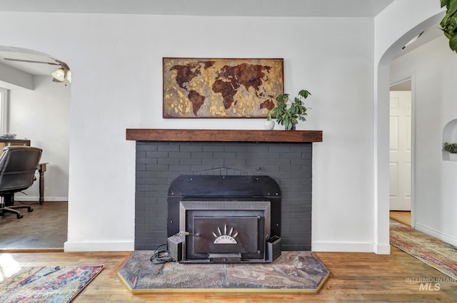 details featuring baseboards, arched walkways, and wood finished floors