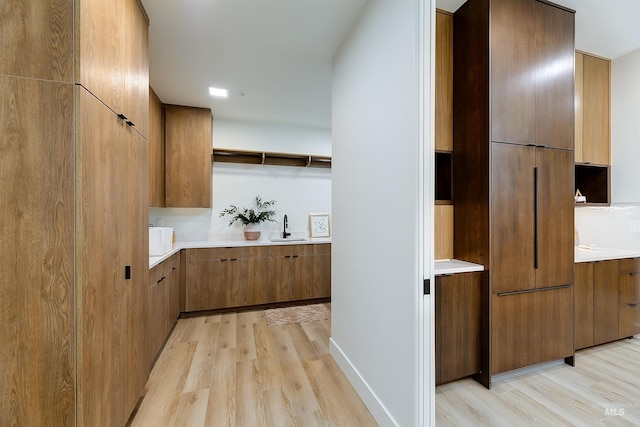 corridor with light hardwood / wood-style floors and sink