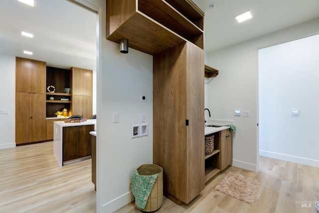 interior space featuring light wood-type flooring, sink, hookup for a washing machine, and electric dryer hookup