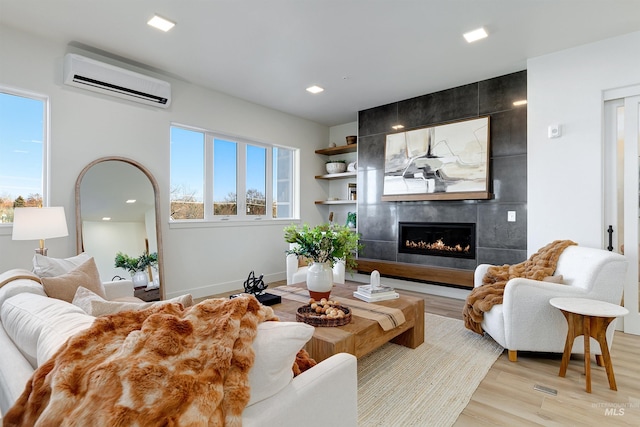 living room featuring a wall mounted AC, a fireplace, and light hardwood / wood-style floors