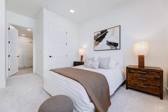 bedroom with connected bathroom and light carpet