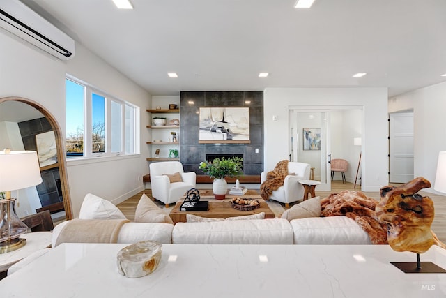 living room with hardwood / wood-style flooring, a tile fireplace, and a wall mounted air conditioner