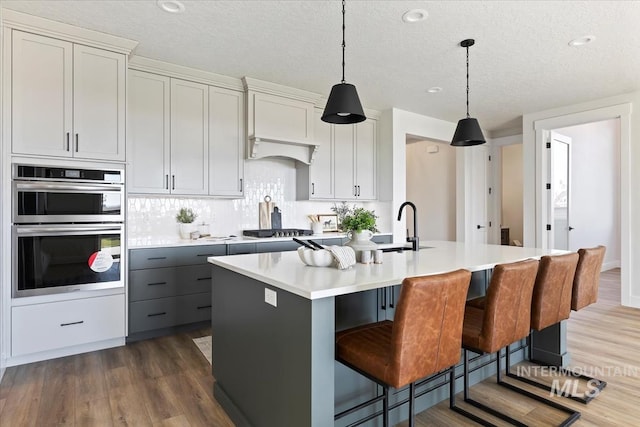 8447 W Happy Day Dr, Meridian, ID 83646 - kitchen with appliances with stainless steel finishes, light countertops, dark wood-style floors, an island with sink, and hanging light fixtures