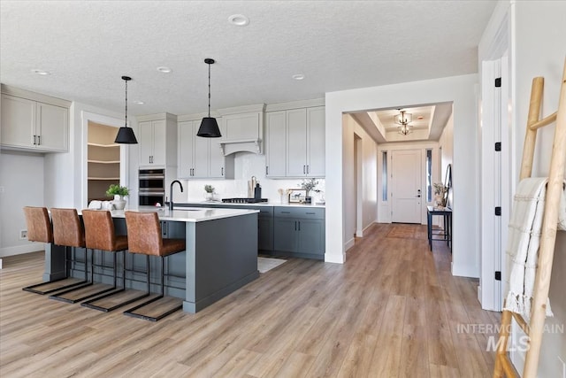 8447 W Happy Day Dr, Meridian, ID 83646 - kitchen featuring stainless steel appliances, light wood finished floors, baseboards, a breakfast bar, and a textured ceiling