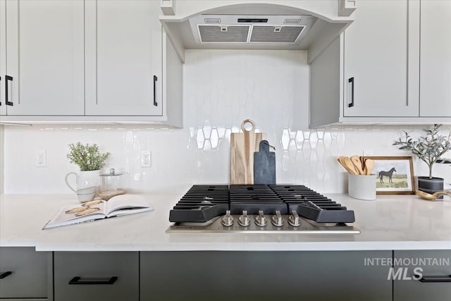 8447 W Happy Day Dr, Meridian, ID 83646 - kitchen with exhaust hood, decorative backsplash, gray cabinetry, and stainless steel gas cooktop