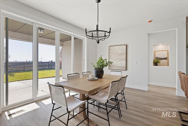 8447 W Happy Day Dr, Meridian, ID 83646 - dining area featuring a chandelier, light wood-style flooring, baseboards, and a textured ceiling