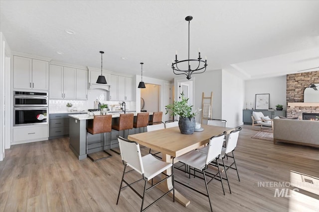 8447 W Happy Day Dr, Meridian, ID 83646 - dining room with a chandelier, light wood-style floors, a fireplace, and recessed lighting