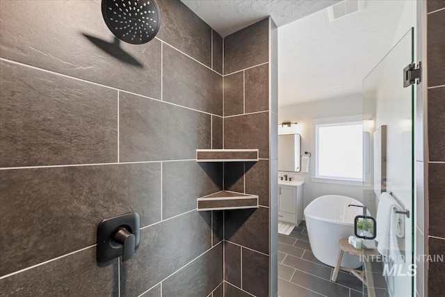 8447 W Happy Day Dr, Meridian, ID 83646 - bathroom featuring a tile shower, a freestanding tub, vanity, and tile patterned floors