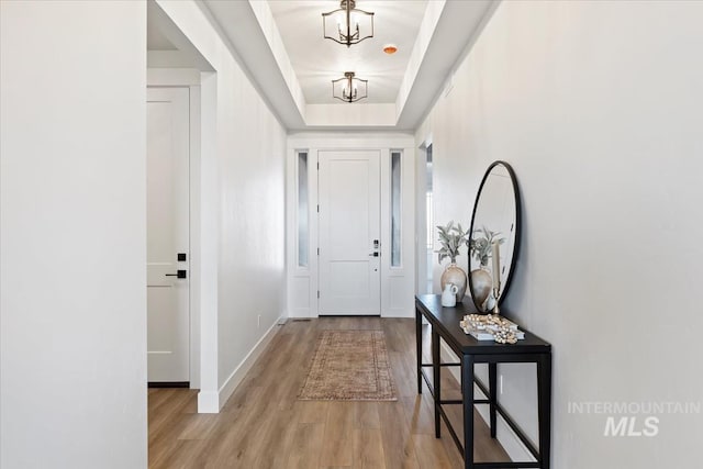 8447 W Happy Day Dr, Meridian, ID 83646 - doorway to outside featuring light wood finished floors, a chandelier, baseboards, and a tray ceiling