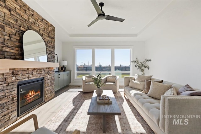 8447 W Happy Day Dr, Meridian, ID 83646 - living room featuring a raised ceiling, wood finished floors, a ceiling fan, and a stone fireplace