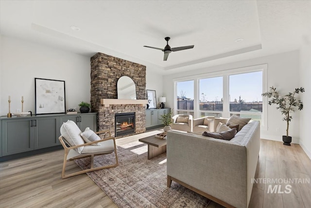 8447 W Happy Day Dr, Meridian, ID 83646 - living room with a tray ceiling, ceiling fan, light wood finished floors, a stone fireplace, and baseboards