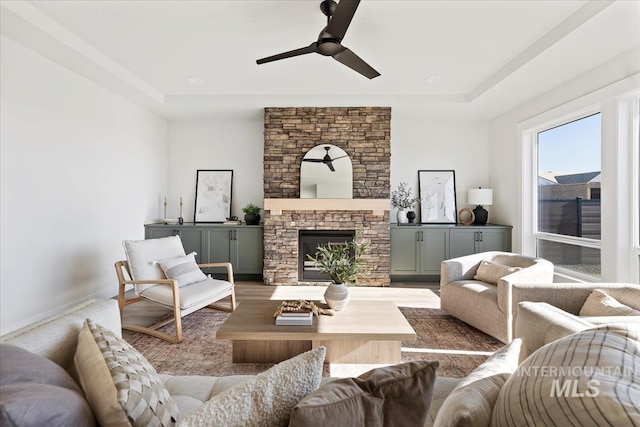8447 W Happy Day Dr, Meridian, ID 83646 - living area with ceiling fan, a raised ceiling, a stone fireplace, and wood finished floors