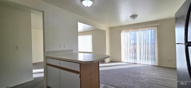 kitchen with white cabinetry, dark carpet, light countertops, and freestanding refrigerator