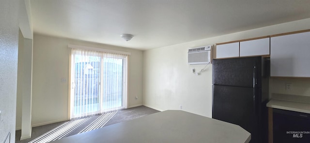 kitchen featuring carpet, light countertops, freestanding refrigerator, white cabinetry, and a wall mounted air conditioner