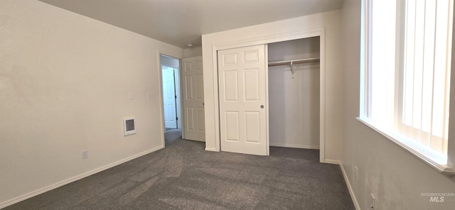 unfurnished bedroom with dark colored carpet, a closet, visible vents, and baseboards