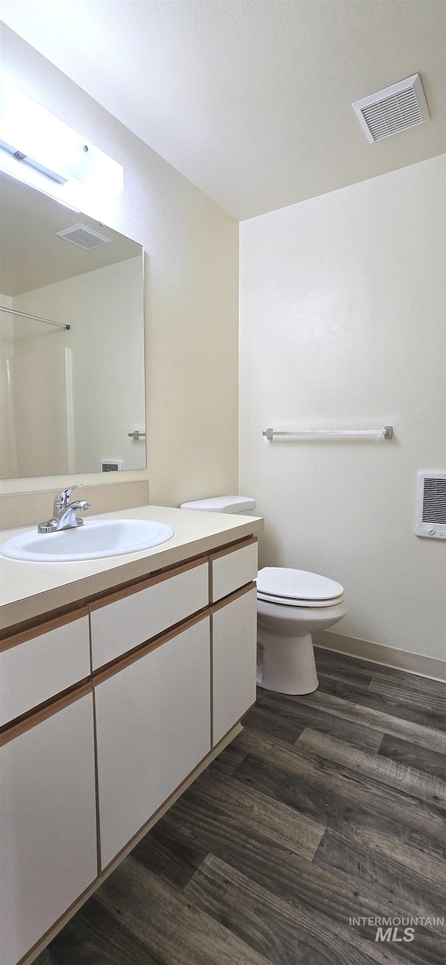 bathroom featuring toilet, vanity, wood finished floors, and visible vents