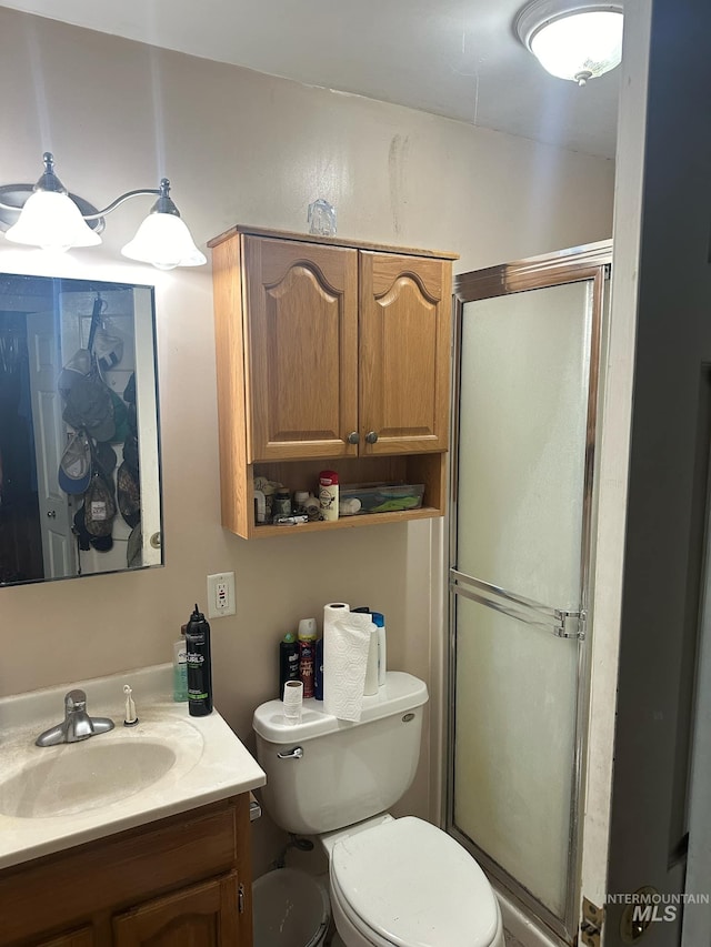 bathroom with vanity, toilet, and a shower with shower door