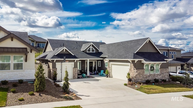 craftsman inspired home featuring stone siding, a garage, a residential view, and concrete driveway
