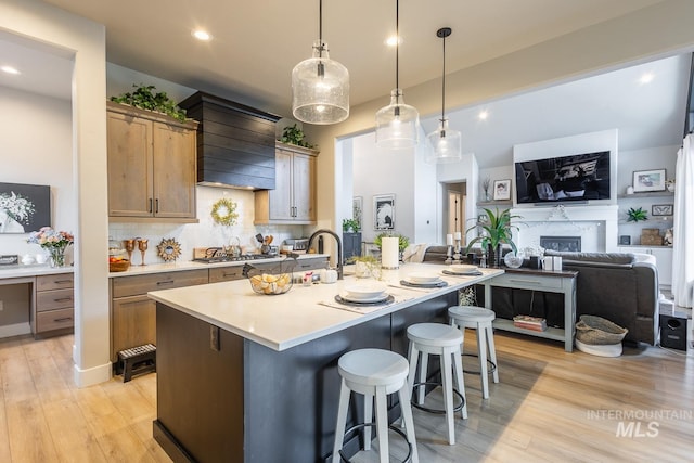 kitchen featuring a kitchen breakfast bar, stainless steel gas cooktop, light wood-style floors, decorative backsplash, and light countertops