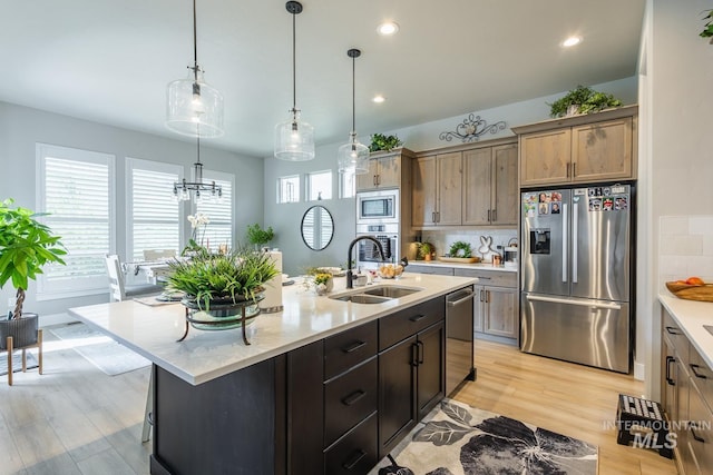 kitchen with tasteful backsplash, appliances with stainless steel finishes, light wood-type flooring, and a sink