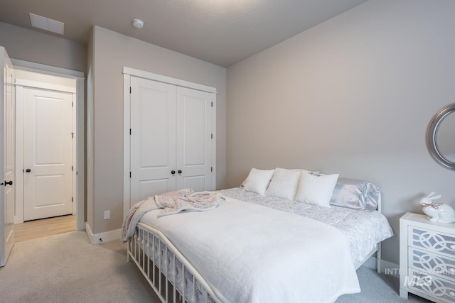 bedroom featuring baseboards, a closet, and light colored carpet