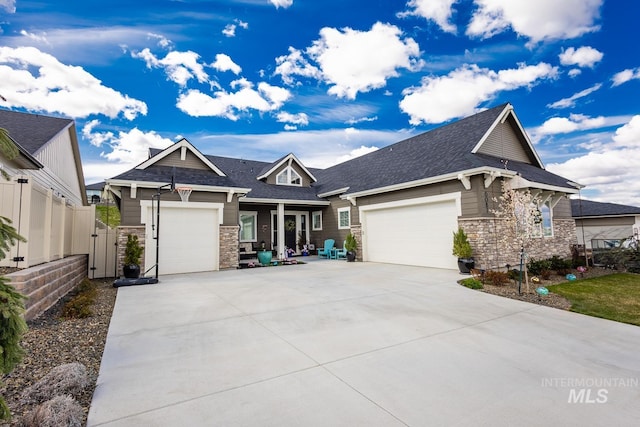 craftsman-style house featuring an attached garage, stone siding, fence, and driveway
