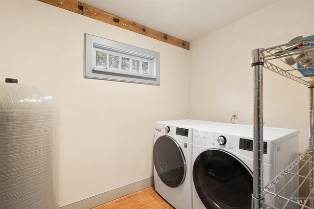 clothes washing area with washer and dryer and light hardwood / wood-style floors