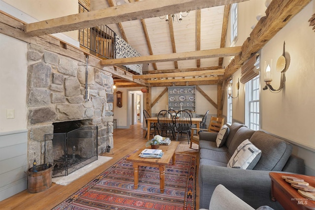 living room with wood-type flooring, vaulted ceiling with beams, a stone fireplace, and wooden ceiling