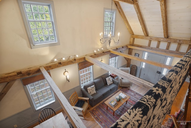 living room with wooden ceiling, high vaulted ceiling, beamed ceiling, wood-type flooring, and a chandelier