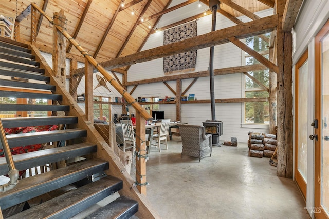 interior space with beam ceiling, high vaulted ceiling, wooden ceiling, concrete floors, and a wood stove