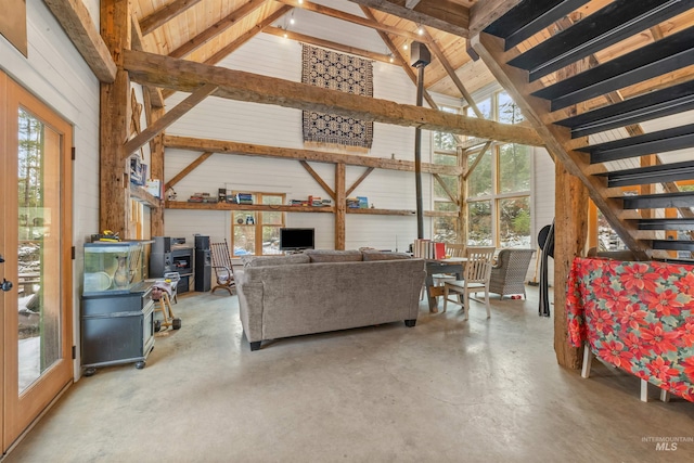 living room with beam ceiling, concrete floors, high vaulted ceiling, and wood walls