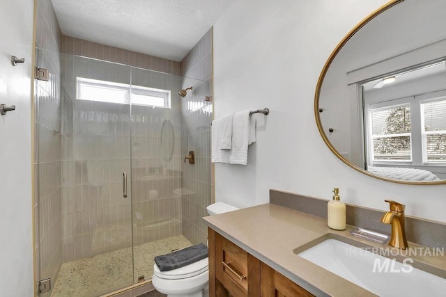 bathroom with toilet, a shower with shower door, a textured ceiling, and a wealth of natural light