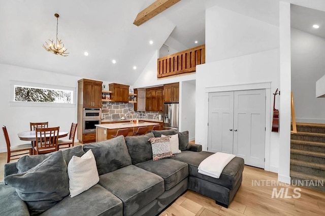 living room featuring a notable chandelier, light hardwood / wood-style floors, beam ceiling, and high vaulted ceiling