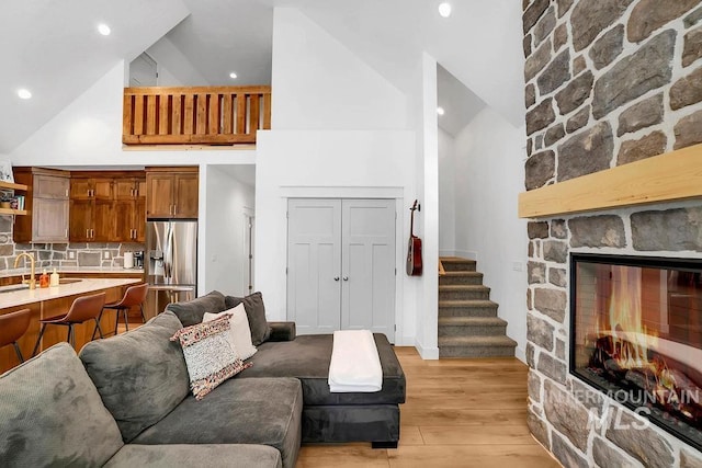 living room with a fireplace, high vaulted ceiling, and light hardwood / wood-style flooring