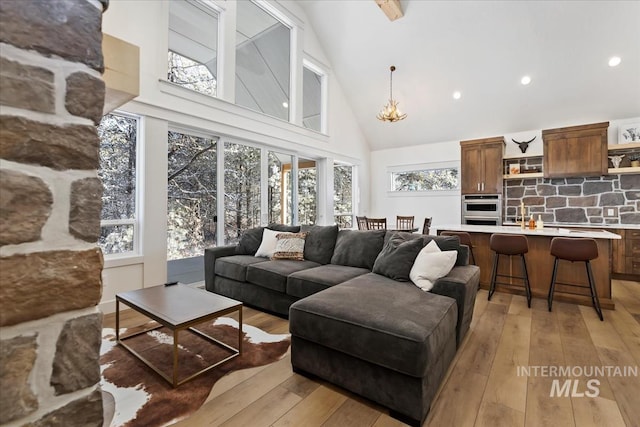 living room featuring high vaulted ceiling, light hardwood / wood-style flooring, and plenty of natural light