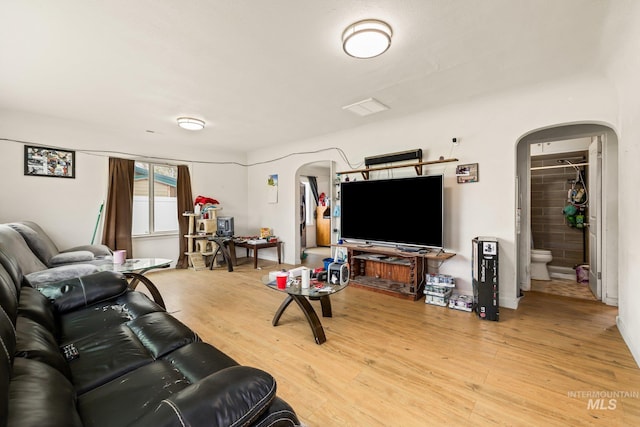 living room featuring arched walkways and light wood-type flooring