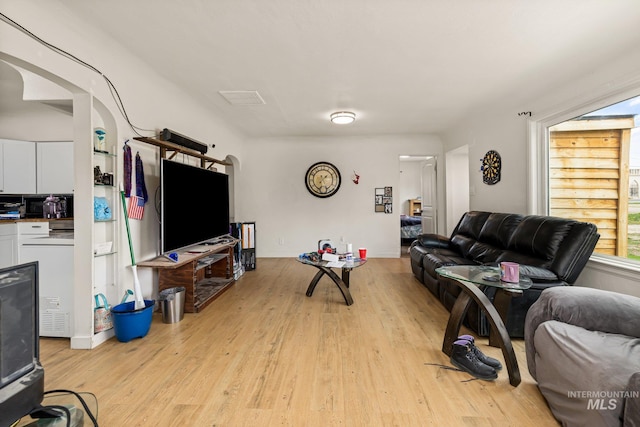 living area featuring light wood-type flooring and arched walkways