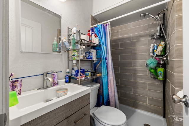 bathroom with toilet, a stall shower, a textured wall, and vanity