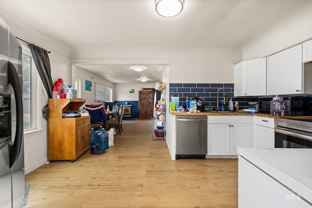 kitchen featuring stainless steel appliances, light wood-style flooring, white cabinetry, and a sink
