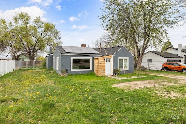 exterior space with fence, a lawn, and roof mounted solar panels