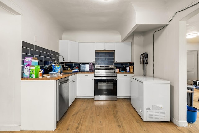 kitchen with light wood-style flooring, backsplash, white cabinets, and stainless steel appliances