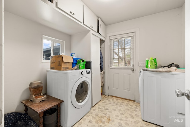 clothes washing area featuring a wealth of natural light, washing machine and clothes dryer, and cabinet space